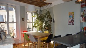 Un coin repas avec une table en bois, des chaises colorées et une plante en pot.