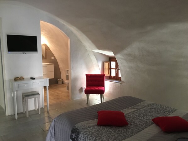 A bedroom with a bed, a desk, a chair, and a TV.
