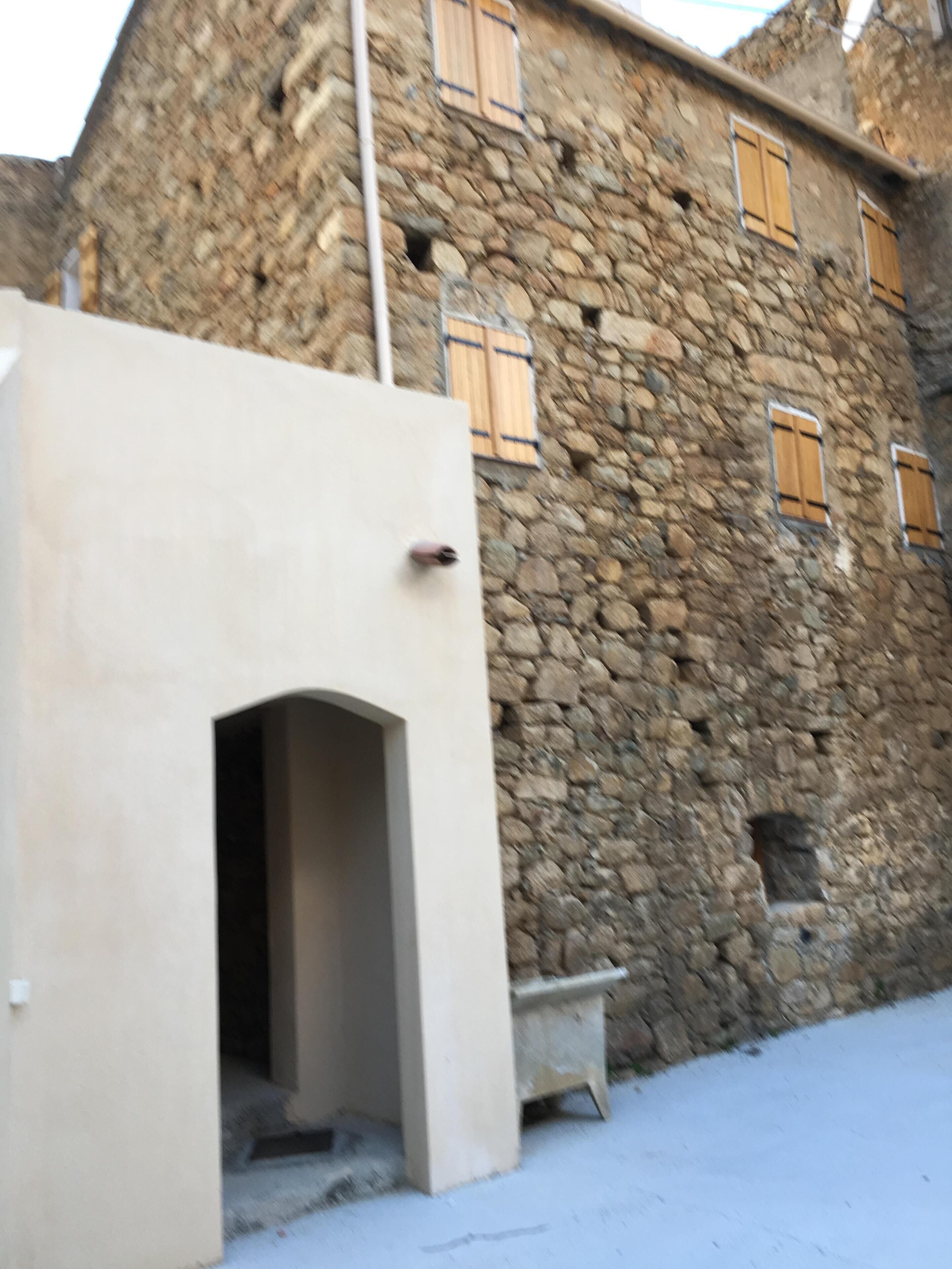 A stone building with a beige entrance and wooden shutters.