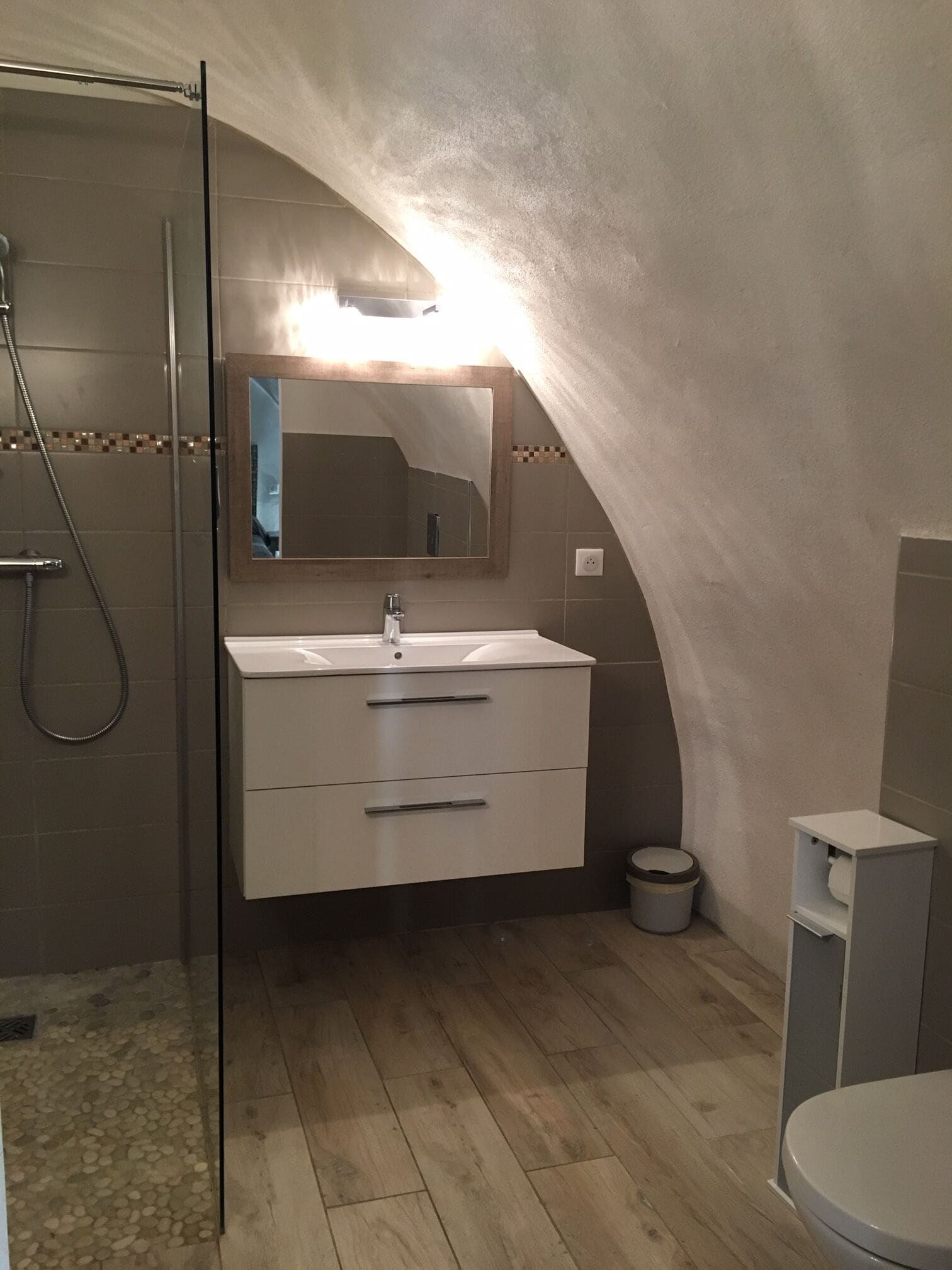 A bathroom with a shower, a sink with a mirror, and a toilet.