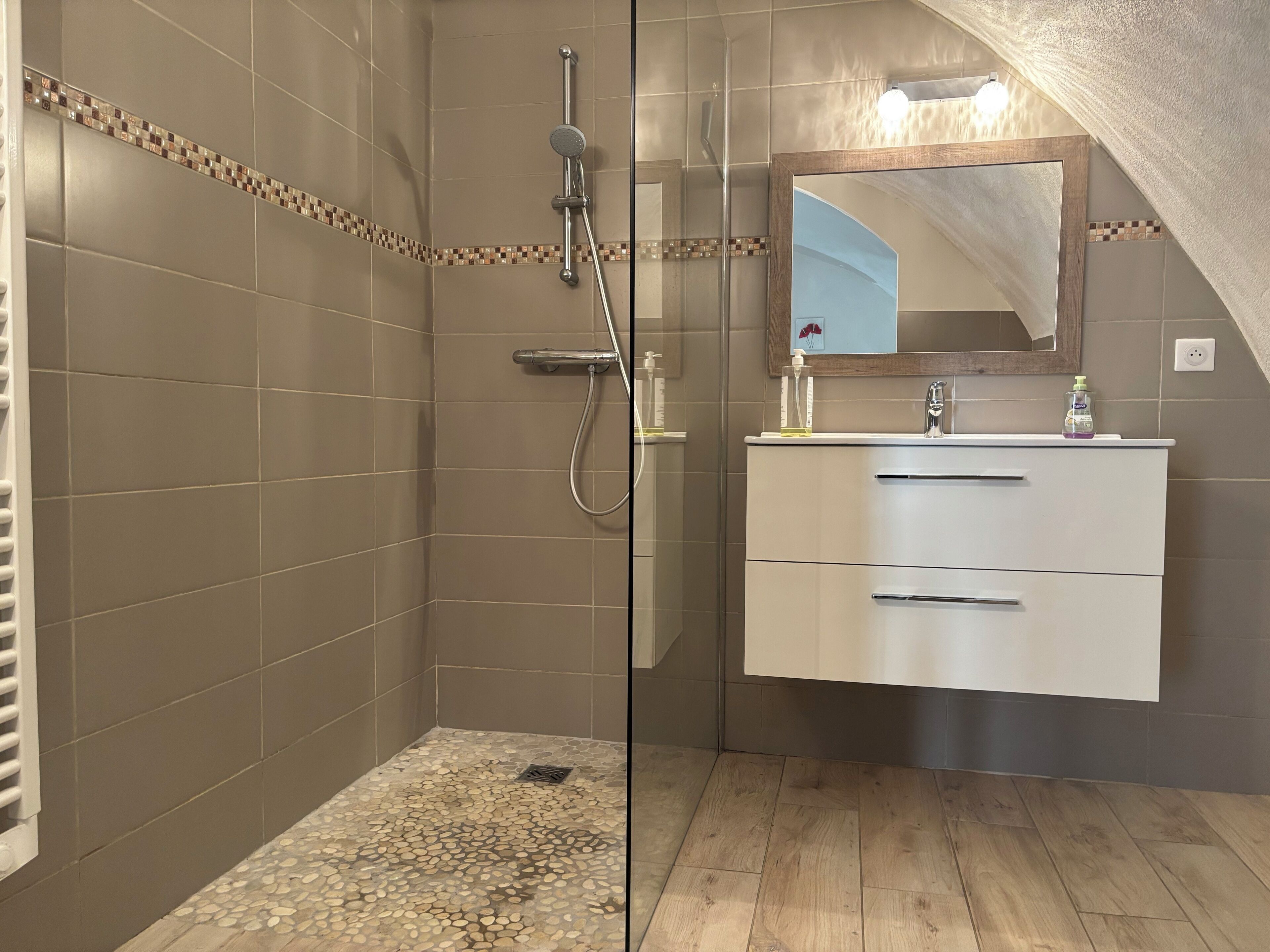 Un baño con ducha, tocador y espejo.