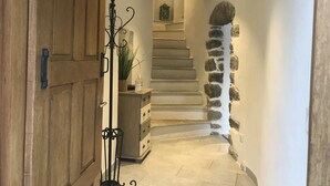 A hallway with a wooden door, a metal stand, a staircase with stone accents, and a small table with a plant. - House of character in Feliceto Corsica, classified 4 stars (Feliceto)