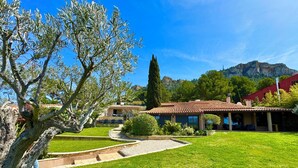 A villa with a terracotta roof, surrounded by a well-maintained lawn and a stone pathway leading to the entrance. - Luxury Villa 5 * - Cassis (Cassis)