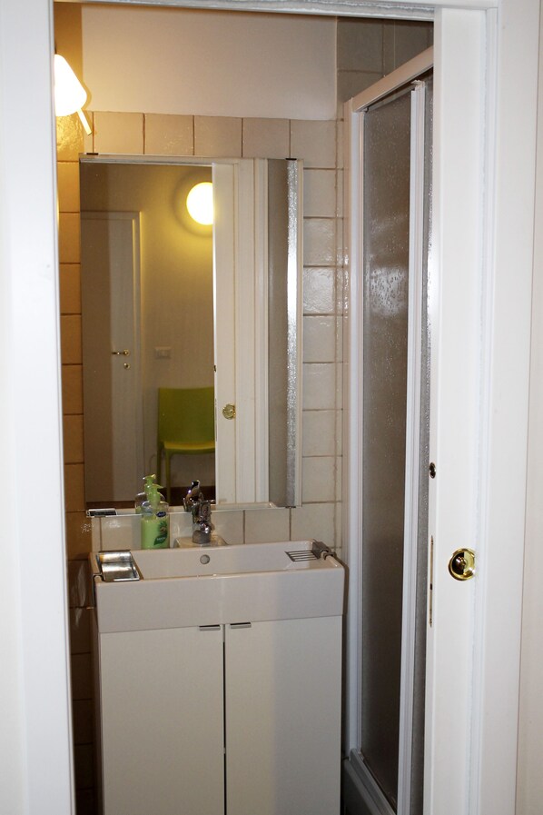 A bathroom with a white sink, mirror, and shower door.