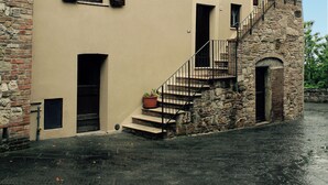 A two-story building with a stone staircase and a small door at the bottom.