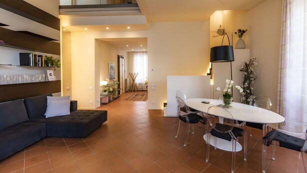 Un salon moderne avec un canapé d’angle, une table à manger avec des chaises et un escalier menant à un niveau supérieur.