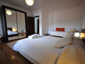 Quarto com uma cama grande, uma cama menor e um espelho.