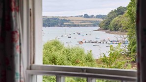 A view through a window of a bay with boats and greenery. - Beautiful cottage with sea views and private beach access (Helston)