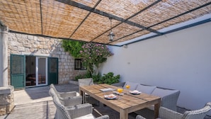 An outdoor patio with wicker furniture, a wooden table, and a thatched roof.