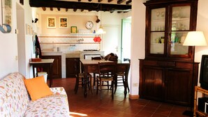 A cozy living room with a sofa and a dining area with a table and chairs. - Ancient house in the hill with a garden and view to the sea. Wi-Fi free (Camaiore, Lucca)