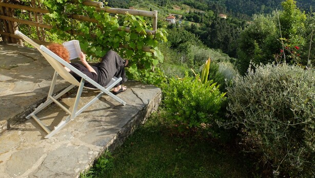 A person reading a book on a bench with a view of a mountainous landscape. - Ancient house in the hill with a garden and view to the sea. Wi-Fi free (Camaiore, Lucca)