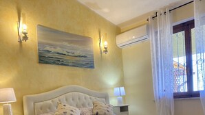 Une chambre à coucher avec un grand lit, deux tables de chevet, un tableau au mur et un appareil de climatisation.