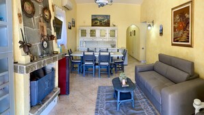 Un salon comprenant un canapé, une table à manger avec des chaises, une cheminée et un coin cuisine.