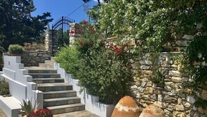 A stone staircase leading up to a gated entrance, surrounded by lush greenery and potted plants. - Fully equipped seafront house with spectacular seaview & small beach right below (Skiathos)