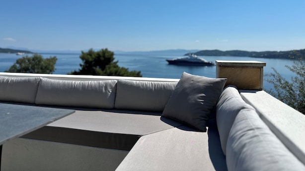 A modern outdoor seating area with a view of the sea and distant land. - Fully equipped seafront house with spectacular seaview & small beach right below (Skiathos)
