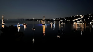 A nighttime harbor with illuminated boats and a distant cityscape. - Fully equipped seafront house with spectacular seaview & small beach right below (Skiathos)