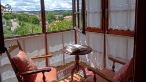 A balcony with a view of a town, a table with a book, and two chairs.