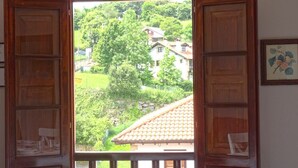 A dining table set for four with a view of a green landscape through open wooden doors.