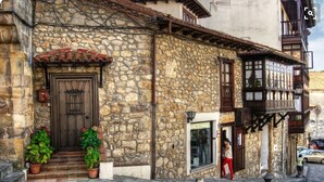 A stone building with a wooden door and steps leading to the entrance.