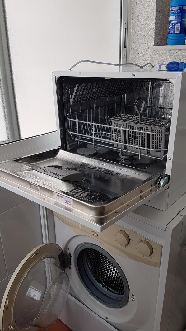 A compact washer and dryer unit with a front-loading washing machine and a top-loading dryer. - BEACHFRONT APARTMENT (Roquetas de Mar)