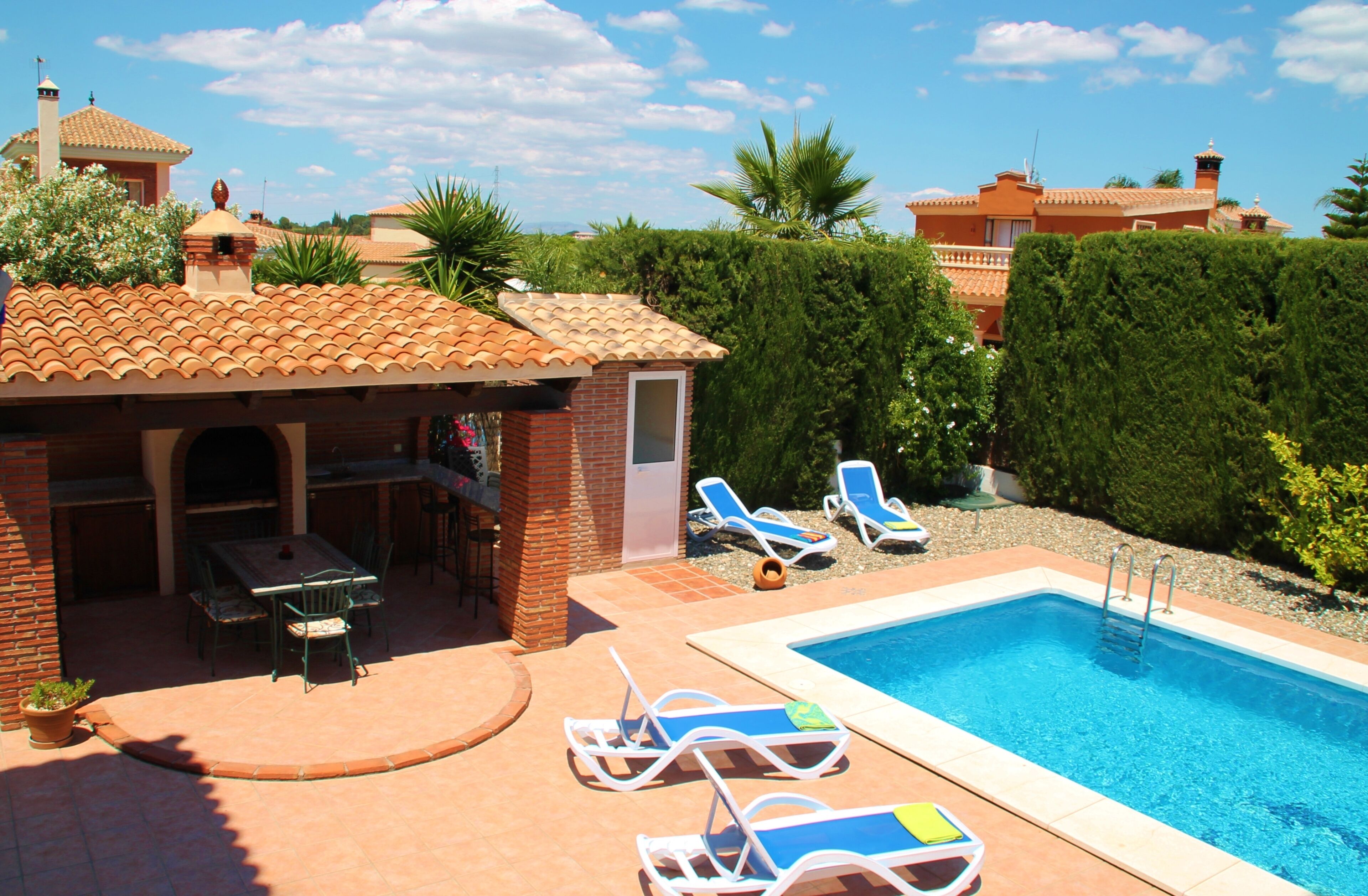 A pool area with lounge chairs and a barbecue setup.