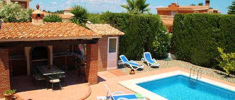 A pool area with lounge chairs and a barbecue setup.