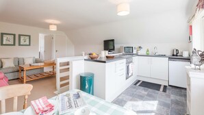 A compact kitchen with a dining area, a television, and a microwave.
