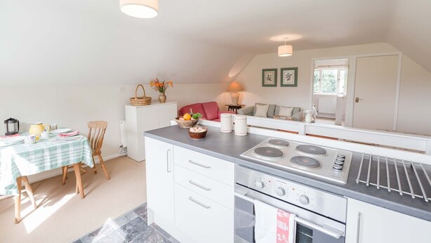 A compact kitchen with a central island, a dining area with a checkered tablecloth, and a cozy seating arrangement.