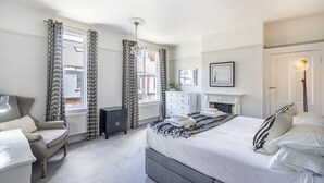 A bedroom with a bed, a dresser, a chair, and a window with curtains.
