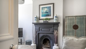 A living room with a fireplace, a framed picture above it, and a door leading to another room.