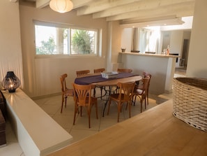 Een eetruimte met een houten tafel en stoelen, een geweven mand en een lamp op een witte toonbank.