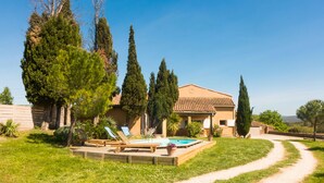 Une maison avec une piscine, un jardin et un chemin de terre.
