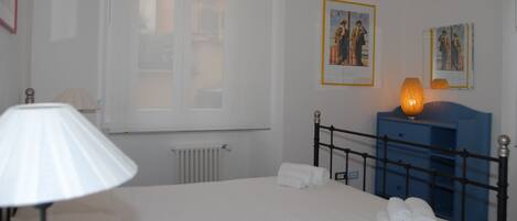 Habitación de hotel con una cama, una lámpara, un aparador y dos cuadros en la pared.