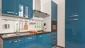 A modern kitchen with blue cabinets, stainless steel appliances, and a range hood. - New and comfortable apartment near the Vatican (Roma)