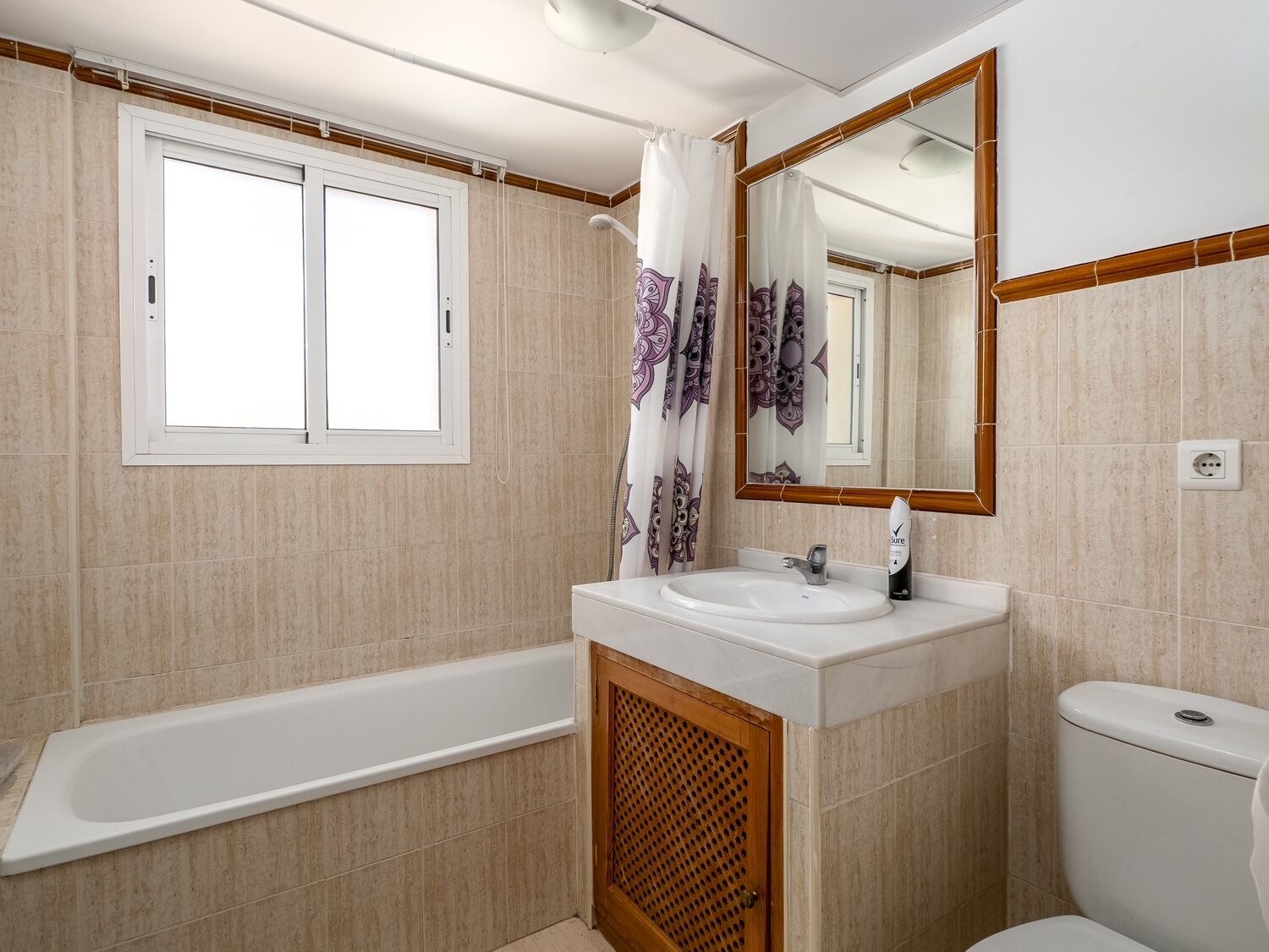 A bathroom with a bathtub, a sink, a toilet, a window, and a shower curtain.