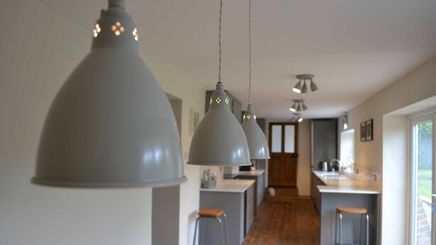 Une cuisine moderne avec des luminaires suspendus, une table à manger en bois et des tabourets de bar.