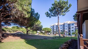 A hotel with a grassy lawn, trees, and a building with balconies. - Apartamento T2, Praia da Falésia, Albufeira (Albufeira)