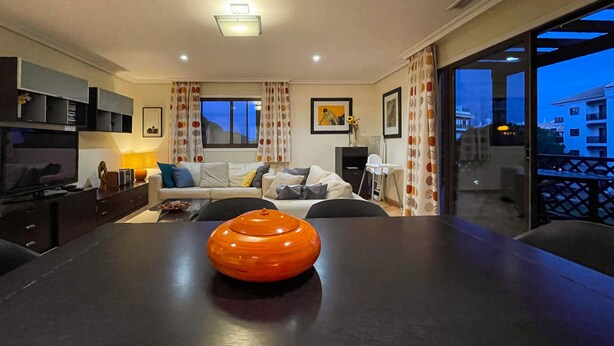 A modern living room with a dark wooden table, a sofa, and a TV. - Apartamento T2, Praia da Falésia, Albufeira (Albufeira)