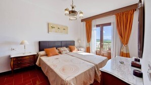 A double bed with a headboard, two bedside tables, a nightstand, a window with curtains, and a view of the outdoors. - Sol y Campo (with wifi) 10 min from the beach (Ariany)