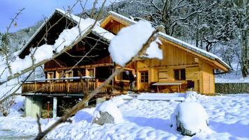 Une cabane en bois dotée d’un balcon, entourée d’arbres couverts de neige.