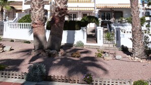 Un edificio con fachada blanca, varios balcones y una entrada con reja.