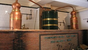Une distillerie dotée d’alambics en cuivre et d’un fût vert, avec des murs en briques et une enseigne indiquant qu’elle a été fondée en 1908.