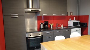 A modern kitchen with stainless steel appliances, a red backsplash, and a wooden dining table. - House / Villa - Saint Maur des Fossés - 30mn from Paris center (Saint-Maur-des-Fosses)