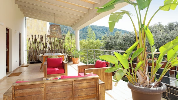 A balcony with wooden furniture, potted plants, and a view of a mountainous landscape. - Elegant Family Villa with Private Pool, Jacuzzi, Spacious Garden & Games Area (Crestatx -Sa Pobla)