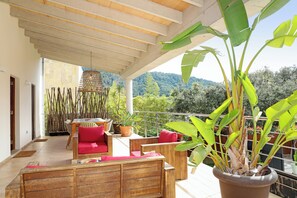 A balcony with wooden furniture, potted plants, and a view of a mountainous landscape. - Elegant Family Villa with Private Pool, Jacuzzi, Spacious Garden & Games Area (Crestatx -Sa Pobla)