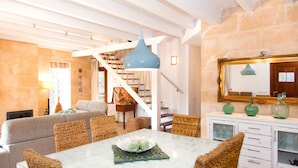 A dining area with a glass table, wicker chairs, and a blue pendant light. - Elegant Family Villa with Private Pool, Jacuzzi, Spacious Garden & Games Area (Crestatx -Sa Pobla)