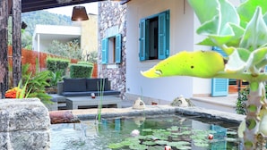 A serene outdoor area with a stone bench, a small pond with lily pads, and a hanging light fixture. - Elegant Family Villa with Private Pool, Jacuzzi, Spacious Garden & Games Area (Crestatx -Sa Pobla)