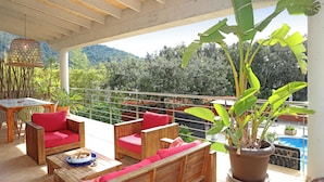 A covered outdoor seating area with wooden furniture and a potted plant. - Elegant Family Villa with Private Pool, Jacuzzi, Spacious Garden & Games Area (Crestatx -Sa Pobla)