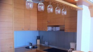A modern kitchen with wooden cabinets, a stainless steel sink, a built-in oven, and pendant lights.