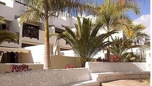 A courtyard with palm trees, a statue, and a stone bench.